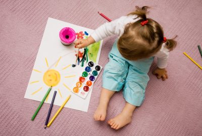 Babyís painting The small beautiful girl paints on a paper